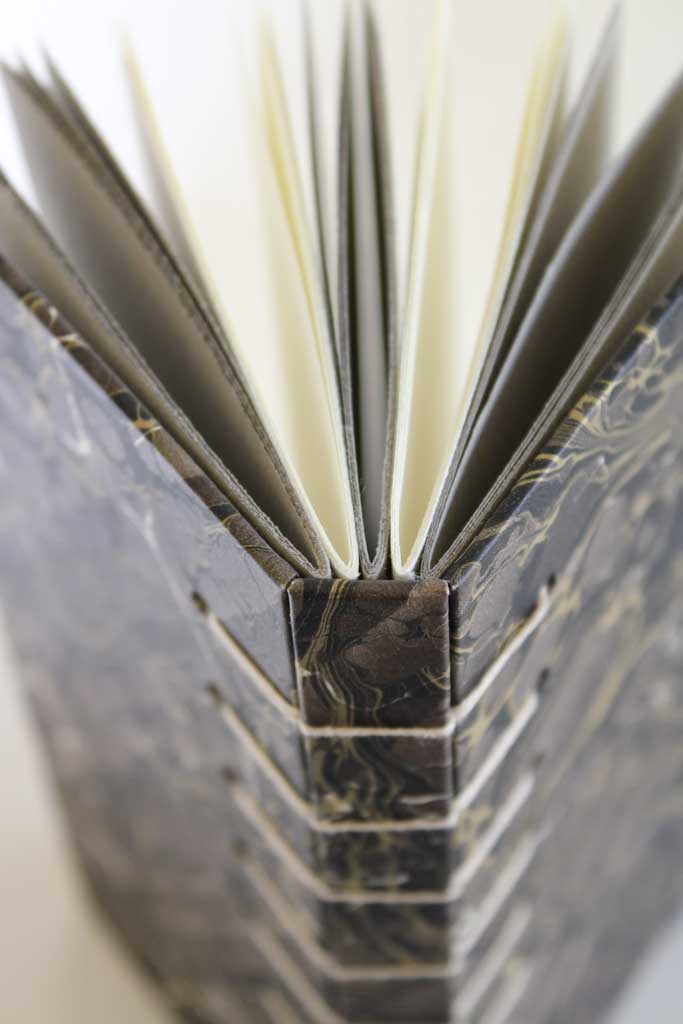Handgebonden boek met marmerpapier en zichtbare naaisteken